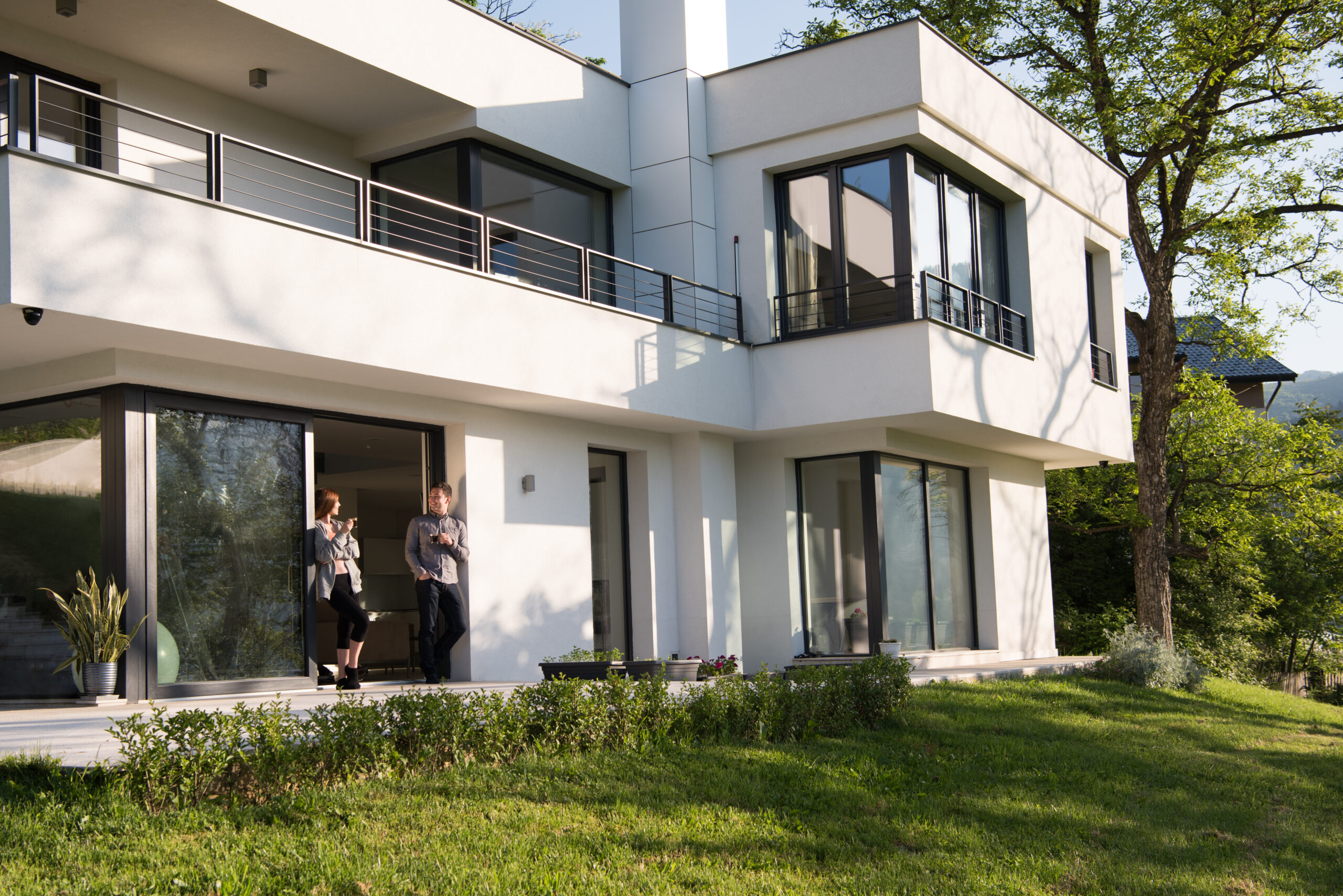 young beautiful handsome couple enjoying morning coffee on the door of their luxury home villa